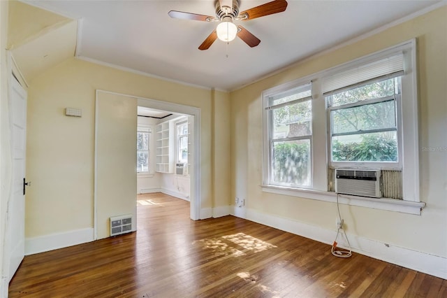 empty room featuring cooling unit, wood finished floors, a ceiling fan, visible vents, and baseboards