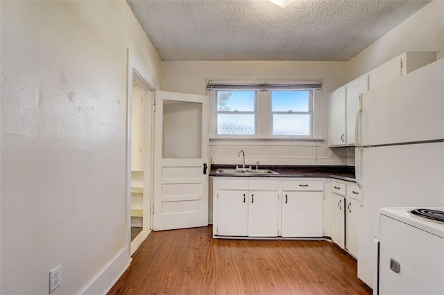 kitchen with dark countertops, light wood-style floors, white cabinetry, and a sink