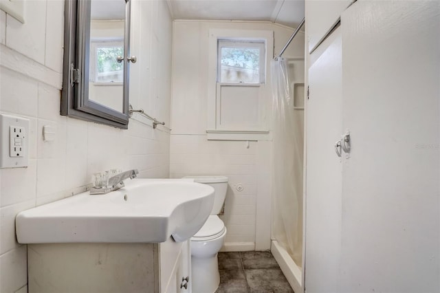 full bathroom with a wealth of natural light, a shower stall, toilet, and tile walls