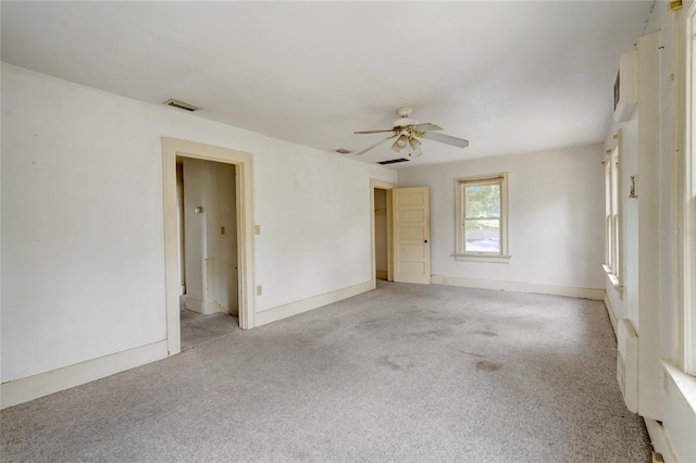 unfurnished room with a ceiling fan, light colored carpet, visible vents, and baseboards