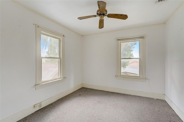 empty room featuring carpet, crown molding, baseboards, and ceiling fan