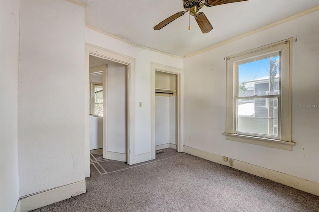 unfurnished bedroom featuring baseboards, a ceiling fan, crown molding, carpet flooring, and a closet