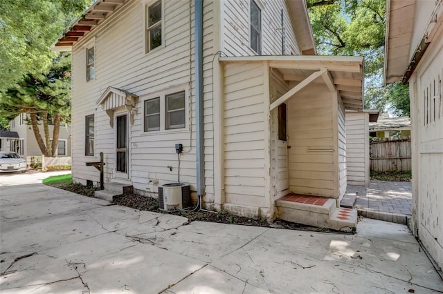 view of property exterior with entry steps, a patio, central AC unit, and fence