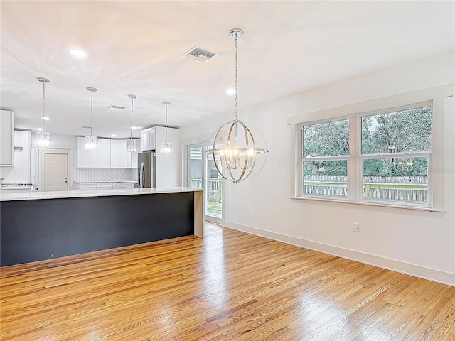 kitchen with light wood finished floors, visible vents, stainless steel refrigerator with ice dispenser, and light countertops