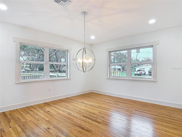 unfurnished room featuring a notable chandelier, light wood-style flooring, visible vents, and baseboards