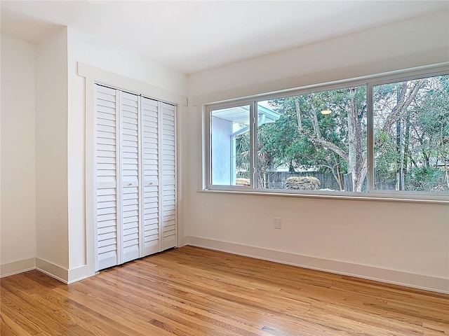 unfurnished bedroom with light wood-style flooring, baseboards, and a closet