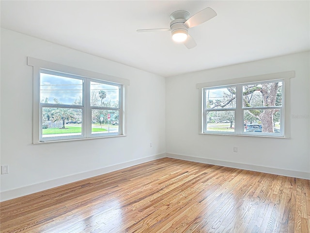 empty room with light wood finished floors, a ceiling fan, and baseboards