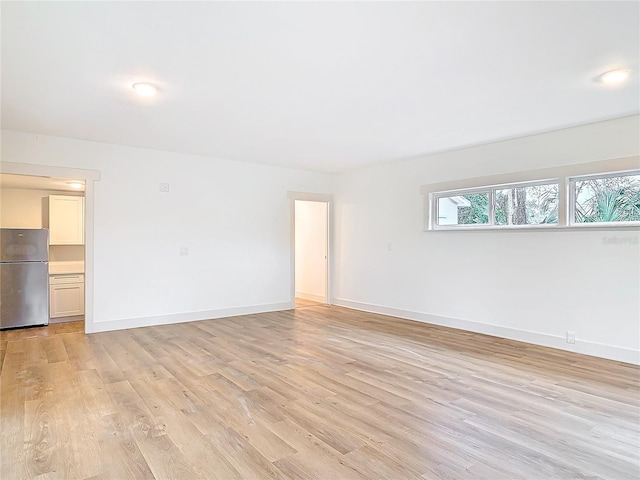 spare room with baseboards and light wood finished floors