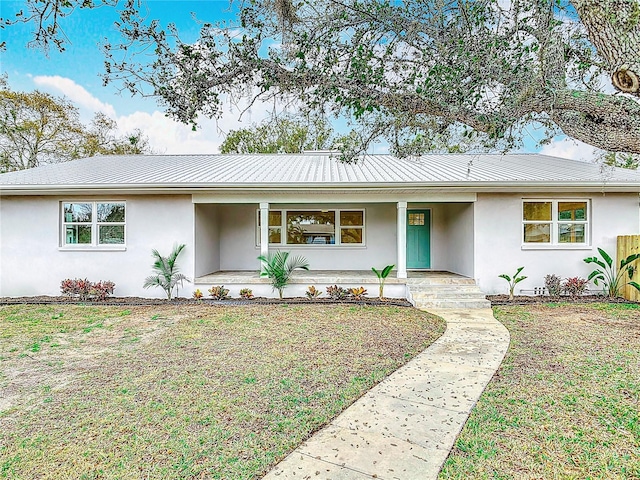 single story home featuring metal roof, a front yard, a porch, and stucco siding