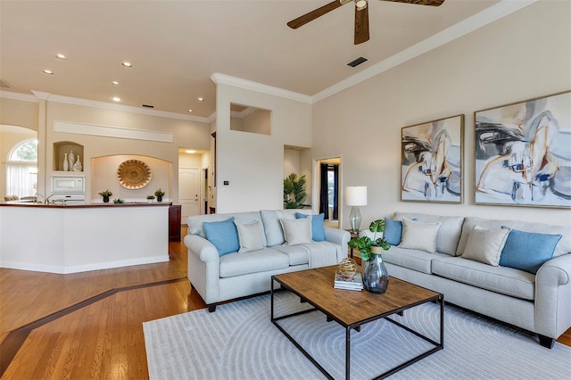 living area with ceiling fan, recessed lighting, wood finished floors, visible vents, and ornamental molding