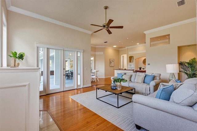 living area with crown molding, light wood finished floors, visible vents, ceiling fan, and baseboards