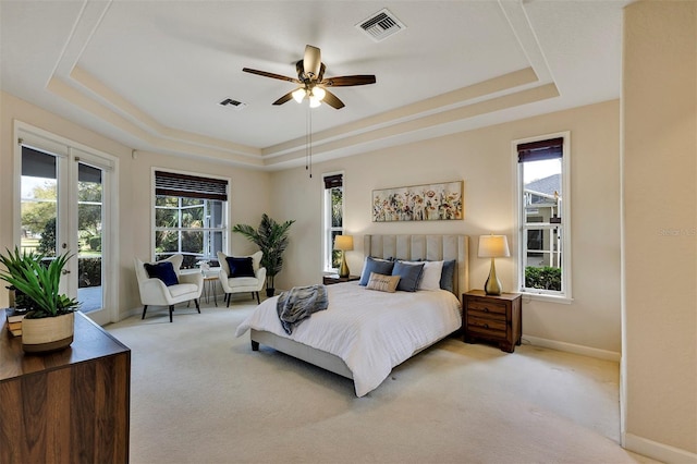 bedroom with access to exterior, a raised ceiling, visible vents, and light colored carpet