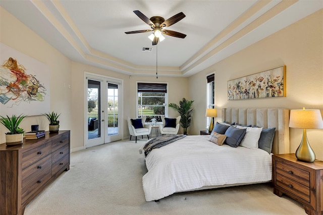 bedroom with access to exterior, a tray ceiling, french doors, visible vents, and light carpet