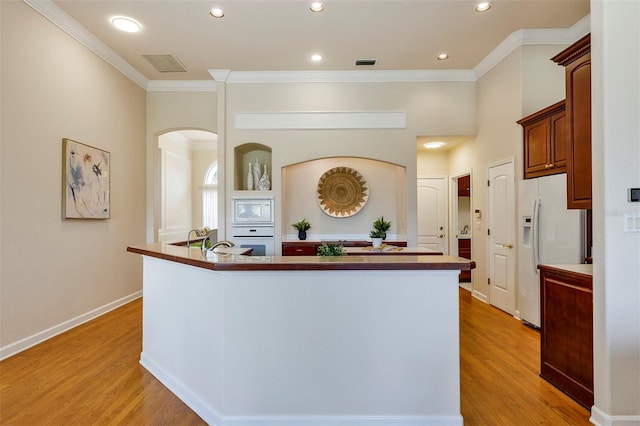 kitchen with ornamental molding, white appliances, visible vents, and light wood finished floors