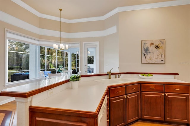 kitchen with light countertops, hanging light fixtures, a sink, and crown molding