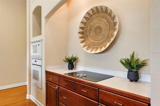 kitchen with light wood-style floors, white appliances, light countertops, and baseboards