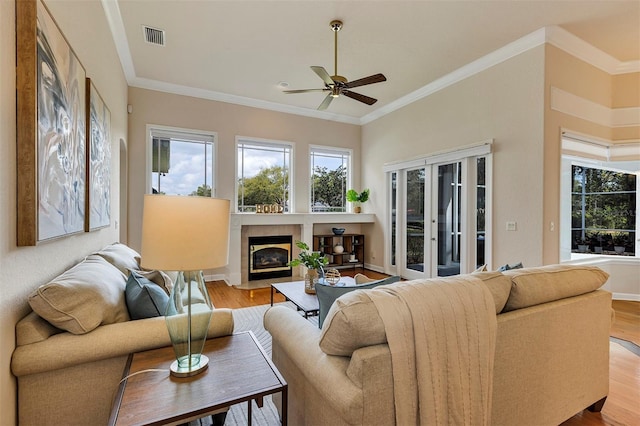 living area with visible vents, wood finished floors, and ornamental molding