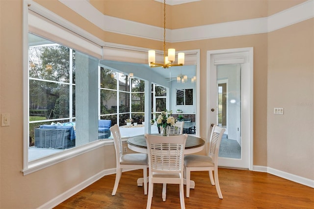 dining space featuring an inviting chandelier, baseboards, a sunroom, and wood finished floors