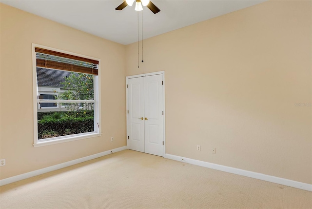 unfurnished room featuring a ceiling fan, light carpet, and baseboards