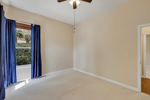 carpeted empty room featuring a ceiling fan and baseboards