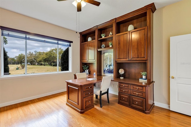 office with a ceiling fan, light wood-type flooring, built in desk, and baseboards