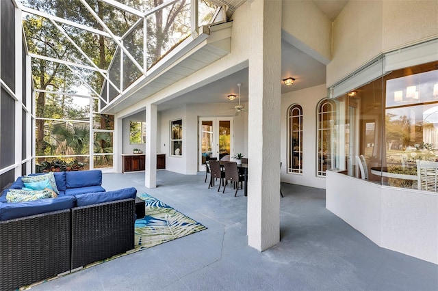 view of patio featuring glass enclosure, ceiling fan, an outdoor hangout area, french doors, and outdoor dining space