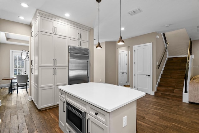 kitchen with built in appliances, dark wood-style flooring, visible vents, and white cabinetry