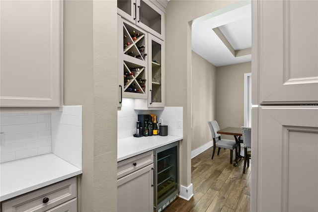 bar featuring tasteful backsplash, wine cooler, dark wood finished floors, and baseboards