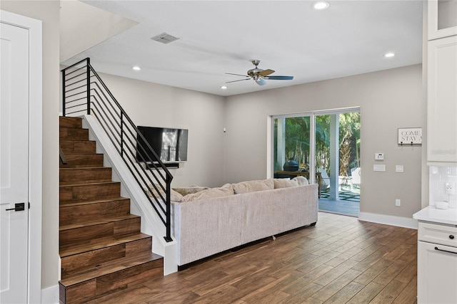 living room featuring ceiling fan, recessed lighting, dark wood-style flooring, visible vents, and stairway