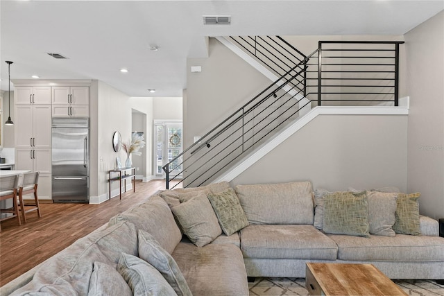 living room featuring stairway, visible vents, and wood finished floors