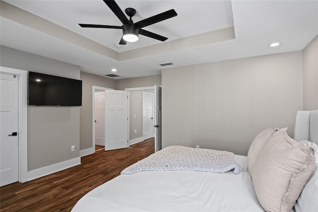 bedroom featuring wood finished floors, a raised ceiling, visible vents, and baseboards