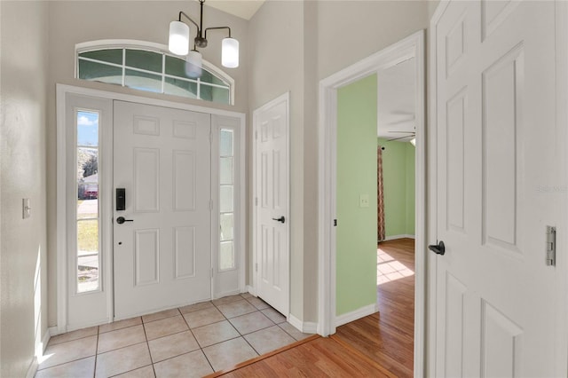 entryway with light tile patterned floors, baseboards, and an inviting chandelier