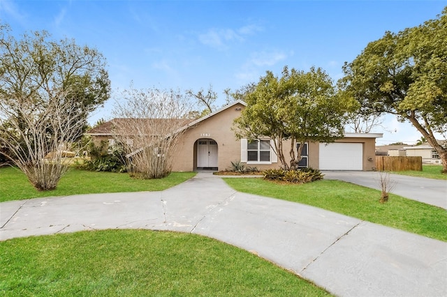 view of front of house with a front yard, driveway, an attached garage, and stucco siding