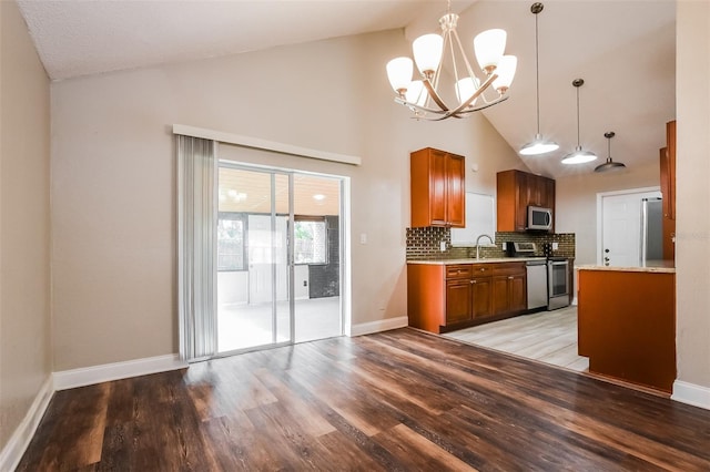 kitchen featuring light wood-style flooring, appliances with stainless steel finishes, brown cabinets, and pendant lighting