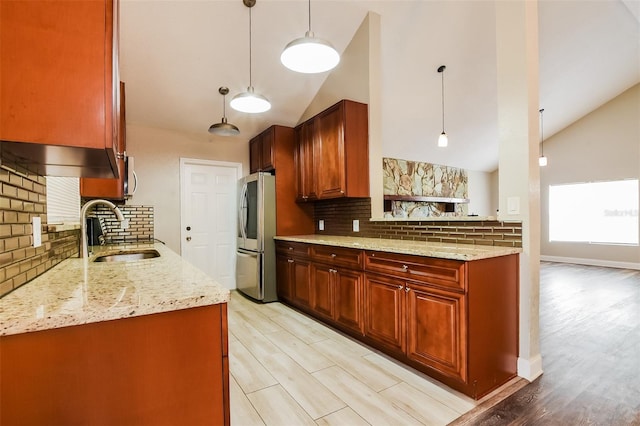 kitchen featuring light stone counters, a sink, hanging light fixtures, and smart refrigerator