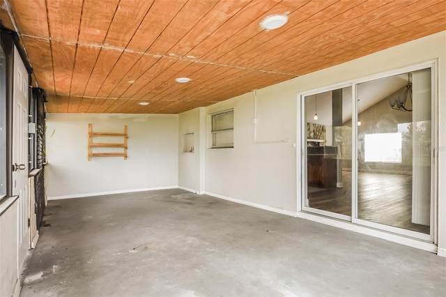 interior space with concrete flooring, wood ceiling, and baseboards