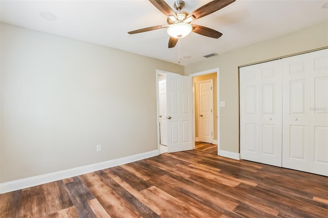 unfurnished bedroom featuring baseboards, visible vents, dark wood finished floors, and a closet