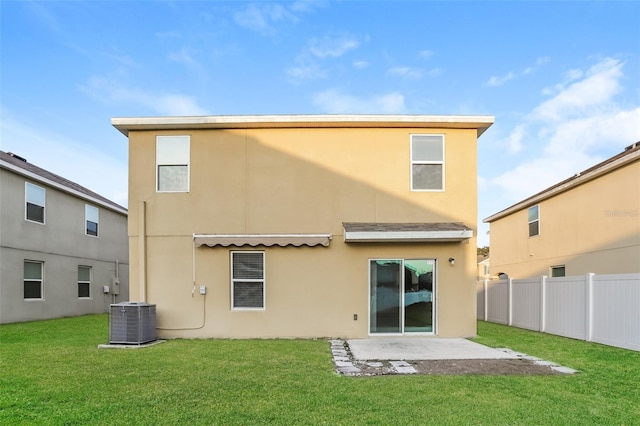 back of property with stucco siding, fence, central AC unit, and a yard