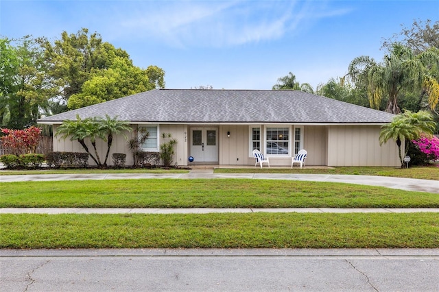 single story home with french doors, a shingled roof, and a front yard