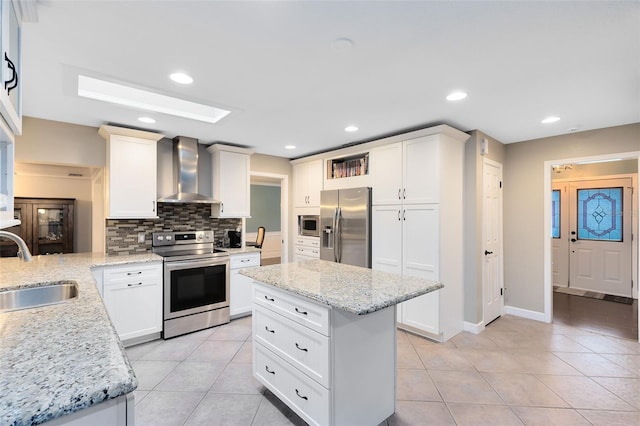 kitchen featuring a sink, appliances with stainless steel finishes, wall chimney exhaust hood, light tile patterned floors, and decorative backsplash