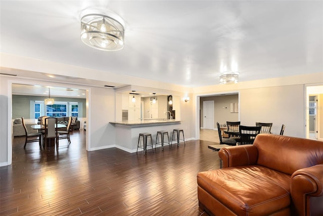 living room featuring a notable chandelier, dark wood-style floors, and baseboards