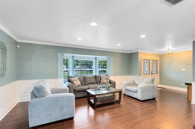 living area with visible vents, dark wood-type flooring, a wainscoted wall, and crown molding