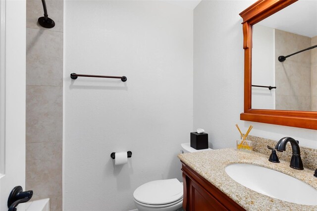 full bath with toilet, vanity, and a tile shower