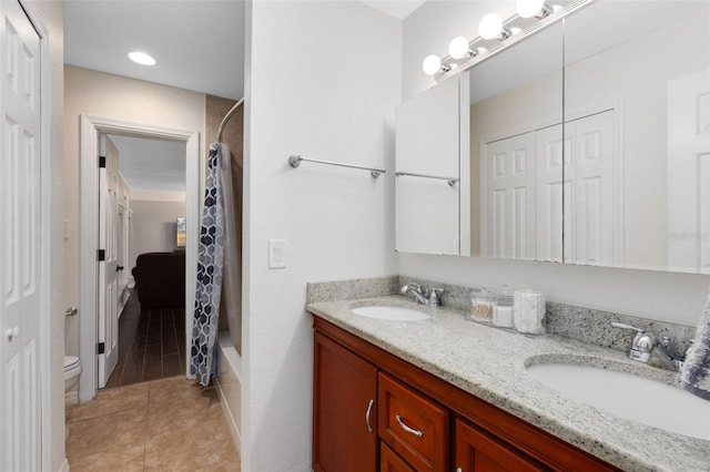 bathroom with double vanity, tile patterned floors, toilet, and a sink