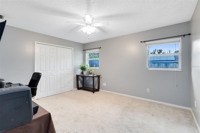 office space featuring visible vents, a ceiling fan, a textured ceiling, carpet flooring, and baseboards