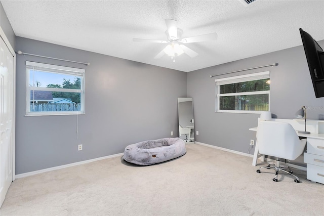 carpeted office space with baseboards, a textured ceiling, and a ceiling fan