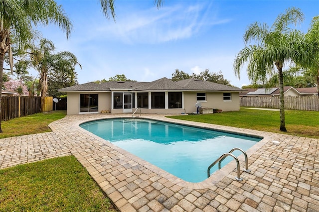 view of swimming pool with a patio, a sunroom, a lawn, and a fenced backyard