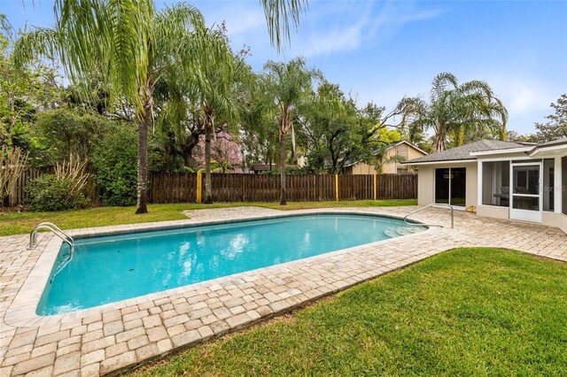 view of pool featuring a fenced in pool, a fenced backyard, a sunroom, a patio area, and a lawn