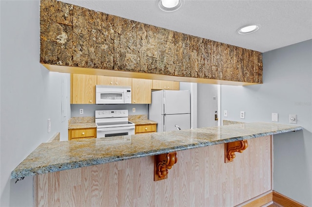 2297 Burnway Rd Unit 2297, Haines City, FL 33844 - kitchen with light stone counters, a breakfast bar area, light brown cabinetry, white appliances, and a peninsula