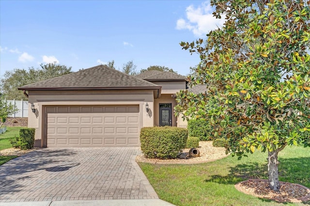 view of front facade with decorative driveway, roof with shingles, stucco siding, an attached garage, and a front yard